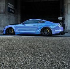 a blue sports car parked in front of a parking meter