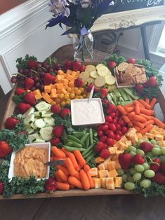 a table filled with assorted fruits and veggies, dips, and crackers