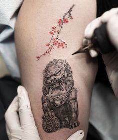 a tattoo artist working on a woman's thigh with an inking tool in her hand