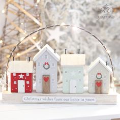 small houses with christmas wreaths on them are sitting in front of a christmas tree