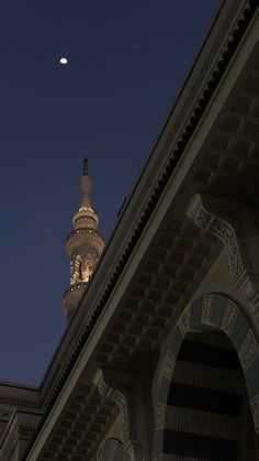 a building with a clock on the top and a moon in the sky above it