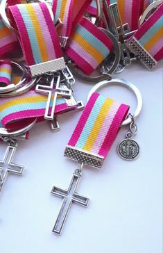 two key chains with crosses on them are laying next to each other and one has a medal