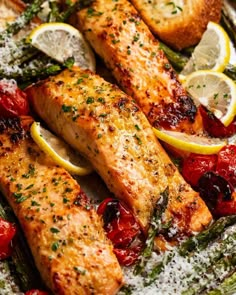 salmon and asparagus on a plate with lemons, tomatoes, and parmesan cheese