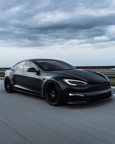 a black tesla car driving down the road