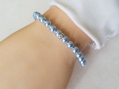 a close up of a person wearing a bracelet with pearls on it's arm