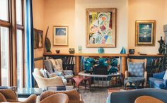 a living room filled with lots of furniture next to a fire place covered in paintings