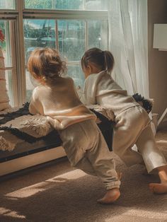 two young children are playing in the window sill