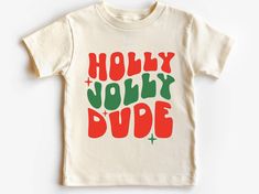 Introducing our "Holly Jolly Dude Christmas Shirt for Kids," designed to add festive cheer and comfort to your child's holiday wardrobe! Key Features: Design: Playful and festive "Holly Jolly Dude" message, capturing the joyful spirit of Christmas with style. Material: Soft and comfortable fabric ensuring a cozy feel throughout holiday activities. Fit: Classic crew neckline and short sleeves for a relaxed and comfortable fit. Versatility: Perfect for holiday parties, family gatherings, and spreading Christmas cheer everywhere they go. Care: Easy-care fabric that is machine washable for convenience and durability. Whether they're decking the halls, singing carols, or opening presents, our Christmas shirt for kids promises to make their holiday season merry and bright. Embrace the joy of Chr Summer Graphic Tee, Look Retro, Look Short, Saved By Grace, Short Styles, Toddler Tees, Holly Jolly, Kid Tees, Boys Shirts