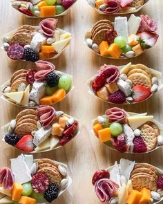 many small bowls filled with different types of cheeses and crackers on top of a wooden table