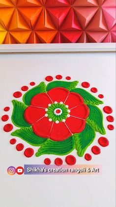 a red flower with green leaves and dots in the center on a white background next to a multicolored origami wall