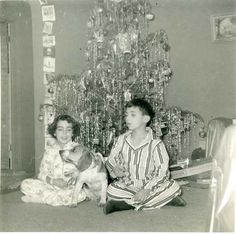 an old black and white photo of two children sitting in front of a christmas tree