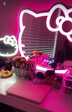 a pink hello kitty desk with makeup brushes and pencils in front of a mirror