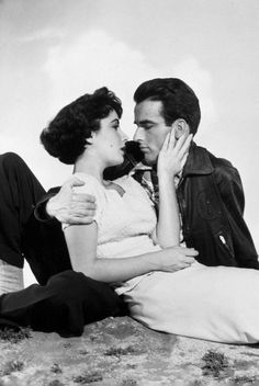 an old black and white photo of a man kissing a woman's face while sitting on the ground