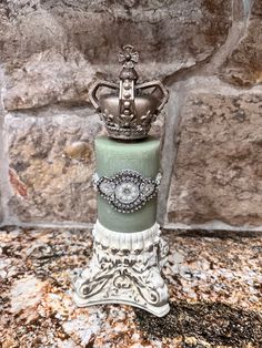 a green and white cake with a crown on top sitting on a marble counter next to a brick wall