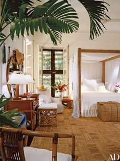 a bedroom with white bedding and lots of palm leaves on the ceiling, along with wicker furniture