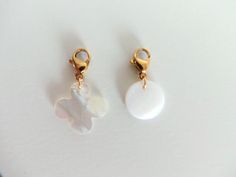 two white and gold earrings sitting on top of a table