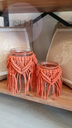 two glass jars with tassels are sitting on a shelf next to decorative pillows