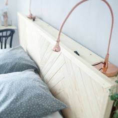 a bed with two lamps on the headboard next to pillows and a table in the background