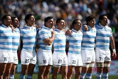 a group of rugby players standing next to each other with their hands in their pockets