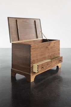 a wooden box sitting on top of a black table next to a white wall and floor