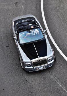 a silver car driving down a road next to a white line on the side of it