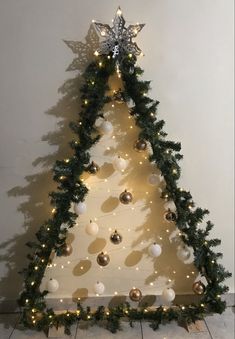 a christmas tree with lights and ornaments on the top is decorated in gold, white and silver