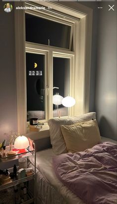 a bed sitting next to a window in a bedroom under a night sky light with a lamp on it