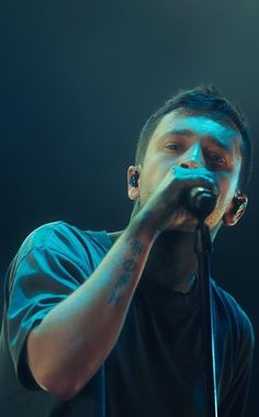 a man holding a microphone in his right hand and singing into the microphone on stage