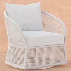 a white wicker chair sitting on top of a floor next to a beige wall