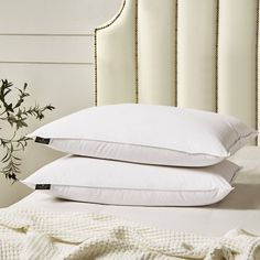 two pillows are stacked on top of each other in front of a white headboard