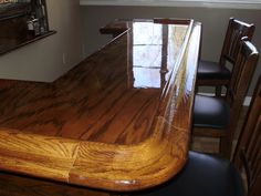 a wooden table with chairs around it in a dining room or bar area, next to a window