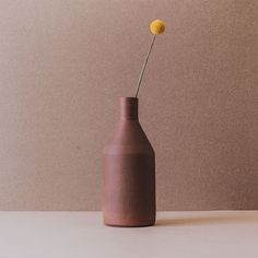 a brown vase with a single yellow flower in it