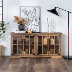 a wooden cabinet with glass doors on the top and bottom, in front of a white wall