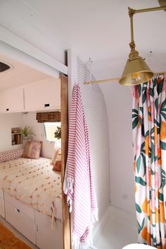 a bed sitting next to a bathroom sink under a light hanging from a ceiling fan