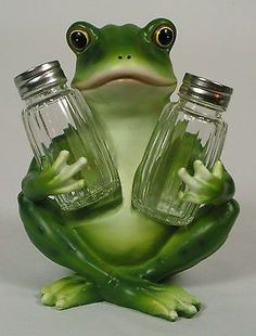 a green frog with two glass jars on its back sitting next to it's legs