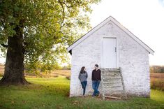 two people standing in front of a small white building with a ladder leaning against it