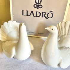 two white ceramic birds sitting in front of a sign that says ladro on it