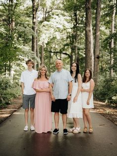 a family posing for a photo in the middle of a road with trees behind them