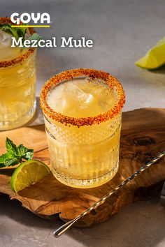 two glasses filled with mexican mules on top of a cutting board next to lime wedges