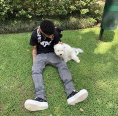 a man sitting in the grass with his dog and petting it's face