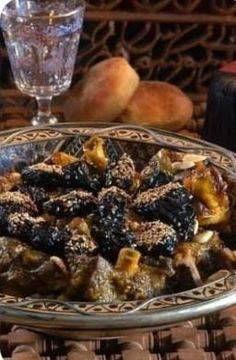 a plate with some food on it next to a wine glass and other items in the background