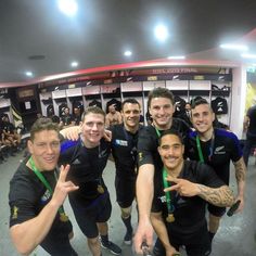 a group of young men standing next to each other in front of lockers with medals around their necks