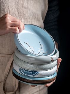 a person holding a stack of plates in their hands