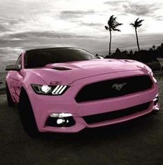 a pink mustang car parked on the beach with palm trees in the backgroud