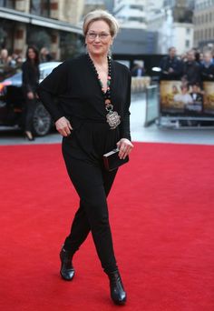 a woman in black is walking down the red carpet