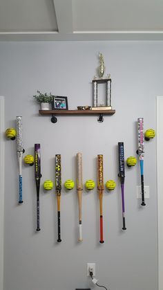 there are many baseball bats hanging on the wall and in front of them is a shelf