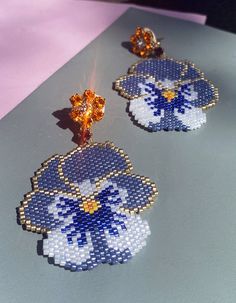 two pairs of blue and white flower shaped beaded earrings sitting on top of a table