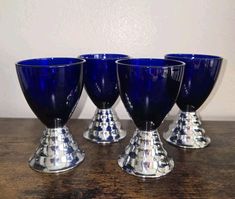 four blue glass goblets sitting on top of a wooden table