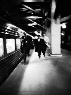 black and white photograph of people walking on a subway platform