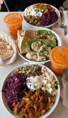 several plates of food on a table with orange juices and drinks in the background